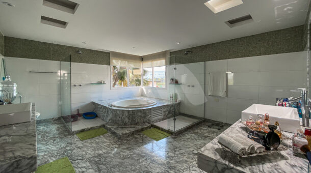 Banheiro de suite master com banheira de hidromassagem, duas bancadas separadas e dois chuveiros separados, acabamento em marmore
