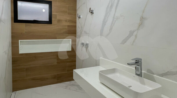 Banheiro com painel de madeira e pia branca< à venda no Alphaville