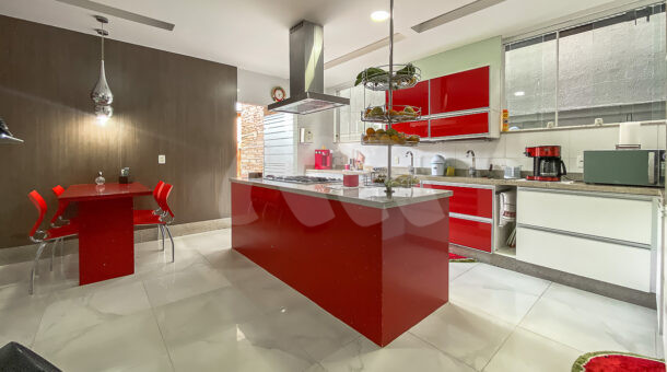 Imagem da cozinha com ilha vermelha da casa à venda na Barra da Tijuca. Casas à venda