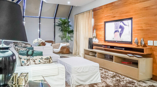 Sala com tv e sofá da casa triplex com localização privilegiada na barra da tijuca