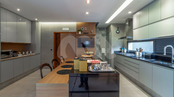 Cozinha super decorada com móveis planejados Favo, ilha de serviço, geladeira, fogão e forno embutidos.