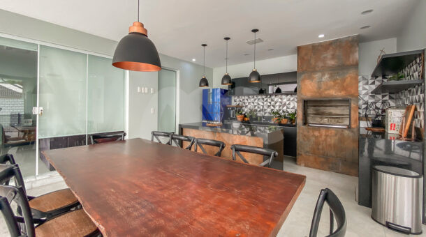 Imagem de área gourmet com mesa de madeira e design industrial em casa à venda na Muller Imóveis RJ
