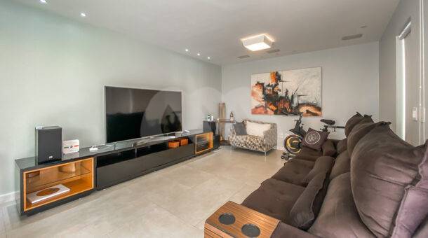 Imagem de sala de tevê com rack e sofá retratil da casa triplex a venda no Quintas do Rio.