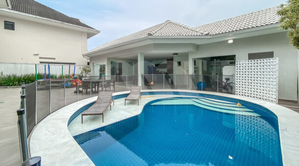 Imagem de piscina com prainha e espreguiçadeiras da casa triplex a venda em luxuoso condomínio.