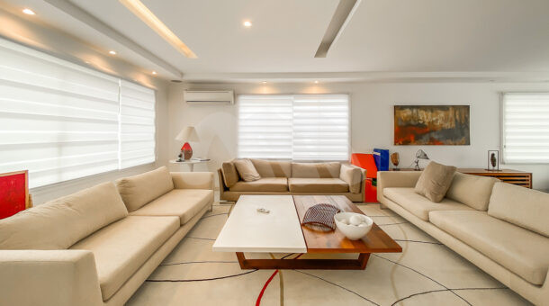 Imagem de sala de estar com 3 sofás beges e mesa de centro de casa contemporânea à venda.
