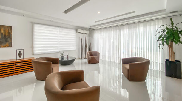 Imagem de sala de estar com poltronas marrom e mesa de centro preta da casa de luxo à venda na Barra da Tijuca .