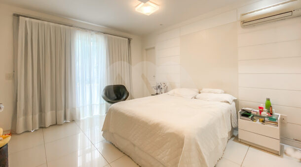 Imagem de quarto suíte com cama de casal, cortinas blackout e voil e mesas de cabeceira da casa à venda em condomínio de alto padrão.