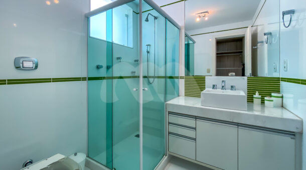 banheiro da segunda suite com box de vidro, um chuveiro e pia branca