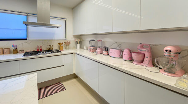 Cozinha com bancada branca em mármore, eletrodomésticos rosas e cooktop
