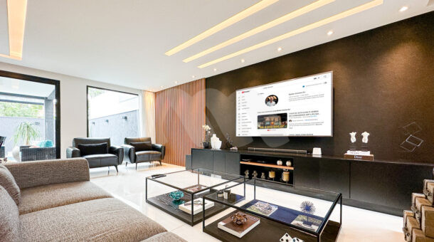 Imagem lateral da sala de TV da mansão moderna à venda na Muller Imóveis RJ.