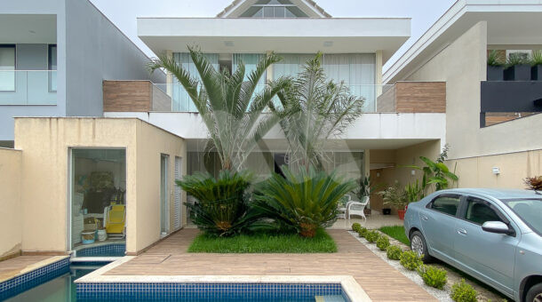 Imagem frontal da casa com garagem da casa à venda em luxoso condomínio de mansões.