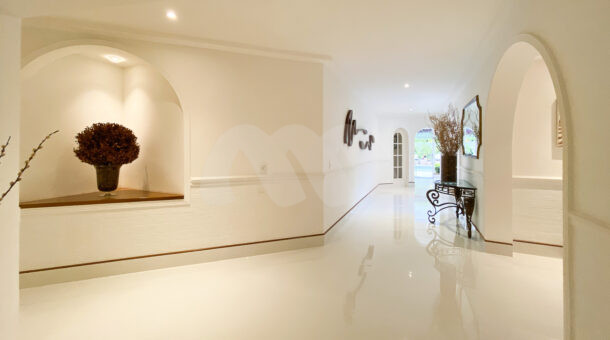 Corredor em piso branco, molduras em parede com decoração atemporal
