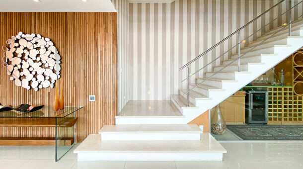 corredor com acesso a escada da casa com painel de madeira e aparador