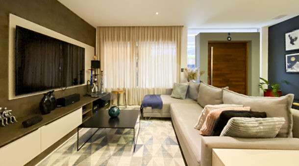 Imagem sala de estar com vista do sofá da casa à venda em luxoso condomínio.