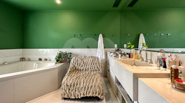 Banheiro de casa à venda com hidromassagem, poltrona e bancada com pia esculpida