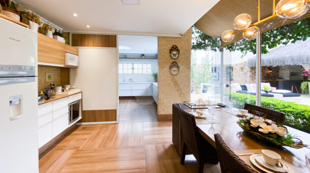 área gourmet com chão em madeira, móveis planejados, bancada e mesa de jantar com mesa posta