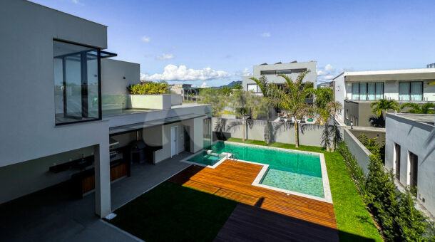 Vista panorâmica da casa com área externa com piscina e deck de madeira e gramado, à venda na barra