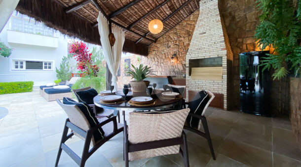 área gourmet com teto abobadado em palha de casa à vendacom bancada e ilha, churrasqueira e mesa de jantar redonda com cadeiras