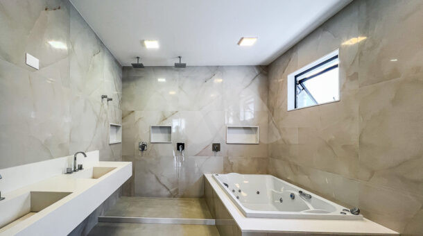 Banheiro cinza da suíte master com cuba dupla, banheira de hidromassagem e chuveiro duplo, à venda no alphaville
