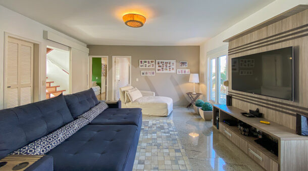imagem da sala com tv e amplo sofá da casa Triplex próximo à praia à venda na Barra da Tijuca na imobiliária de luxo RJ