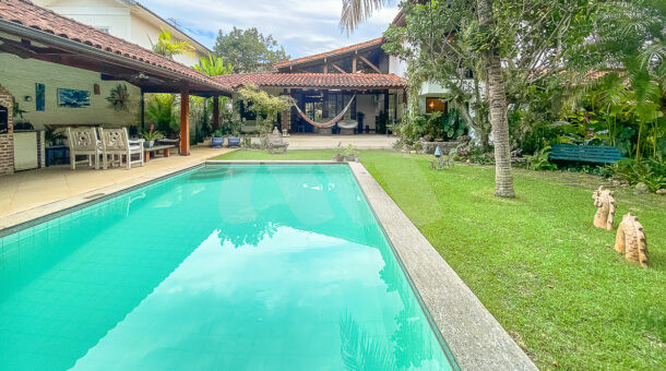 Imagem frontal da piscina com vista da entrada da casa à venda em prestigioso condomínio.