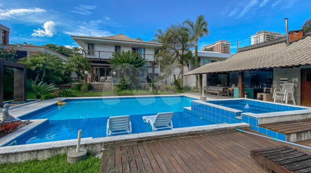Imagem da área externa com piscina e deck de madeira da excelente casa clássica á venda na Barra da Tijuca