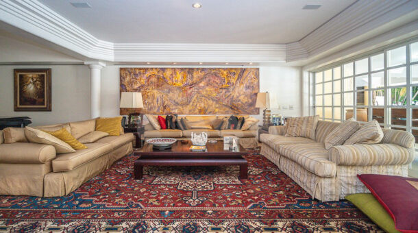 Imagem do sofá com vista do grande tapete da mansão moderna à venda na Muller Imóveis RJ.