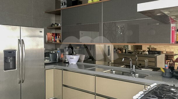 Imagem lateral da cozinha com vista da pia e geladeira da mansão contemporânea à venda.