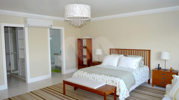 Imagem de amplo quarto com cama de casal de madeira e moveis planejados da casa triplex a venda