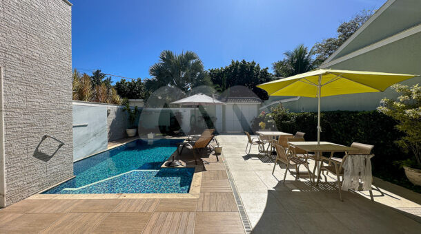 Imagem frontal com vista da piscina da casa à venda em prestigioso condomínio.