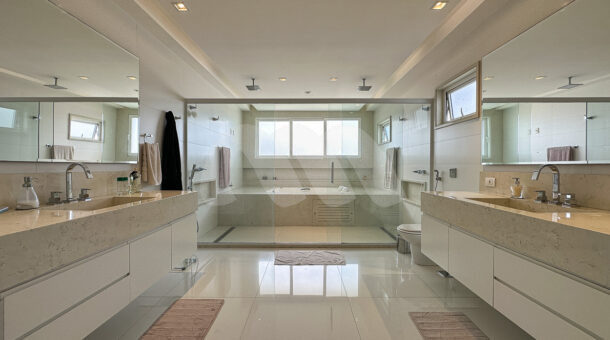 Imagem de banheiro de suite master com duas bancadas, dois chuveiros e banheira de hidromassagem em casa triplex a venda
