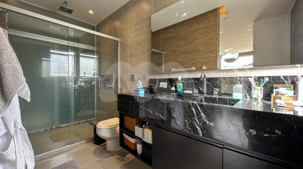 Imagem de banheiro com bancada de marmore preto e boc com chuveir