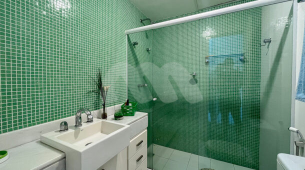 Imagem lateral do banheiro com detalhes em verde do imóvel à venda em condomínio de mansões.