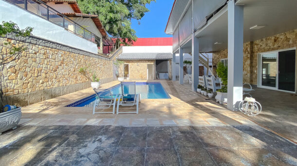 Imagem frontal da piscina com vista da mansão moderna à venda na Muller Imóveis RJ.