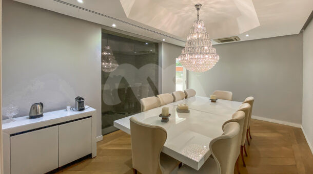 Imagem de sala de jantar com ampla mesa branca e lustre em casa a venda