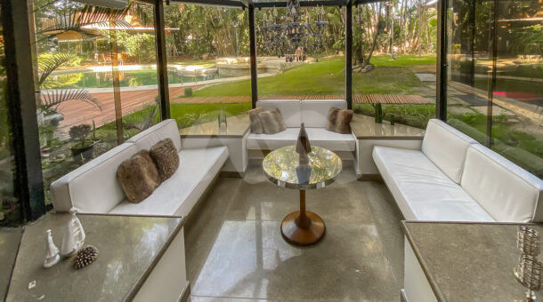 Imagem de gazebo de vidro com sofás e mesa de centro em casa triplex à venda na barra da tijuca