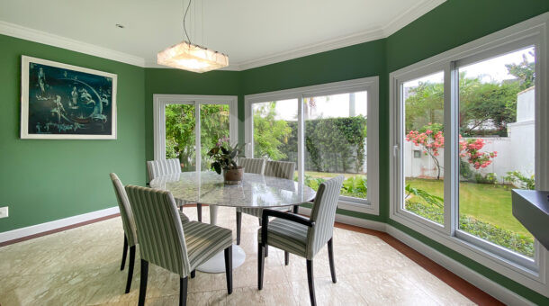 Imagem de sala de jantar cim janelas com vista para jardim frontal e mesa de jantar com lustre em casa triplex a venda na barra