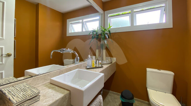 Imagem de lavabo com bancada e cuba e parede coral da casa a venda na barra da tijuca