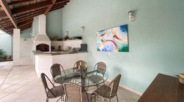 Imagem de varanda com área gourmet, churrasqueira e mesa redonda de vidro em casa a venda