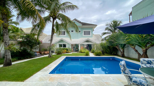 Imagem de piscina com mesa ombrelone e casa verda triplex a venda