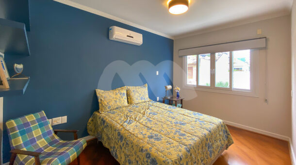 Imagem de quarto com cama de casal, poltrona e estantes da casa triplex a venda