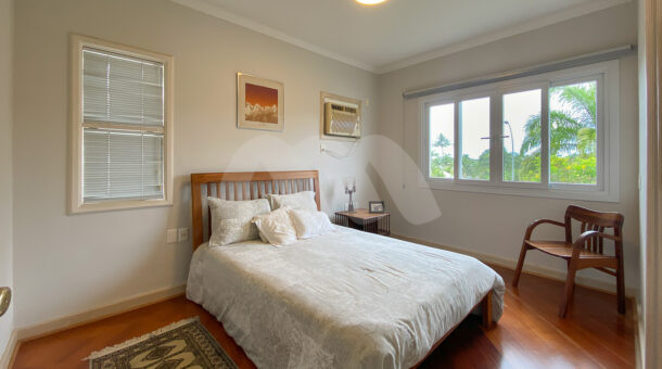 Imagem de quarto com cama de casal em madeira, cadeira e piso de madeira da casa triplex a venda
