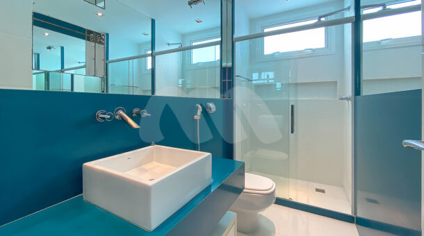 Imagem lateral do banheiro com detalhes em azul do imóvel de luxo à venda.