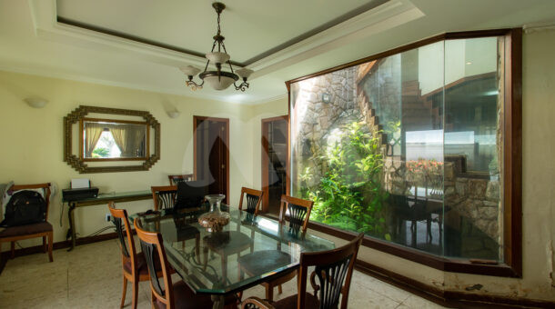Imagem da sala de jantar ao lado de um jardim de inverno da belissima casa no Recreio na imobiliária de luxo RJ