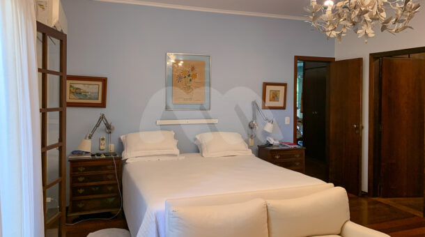 Imagem lateral do quarto com vista da cama da casa à venda em condomínio de alto padrão.