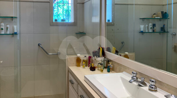 Imagem lateral do banheiro com vista da pia da casa à venda em luxoso condomínio de mansões.