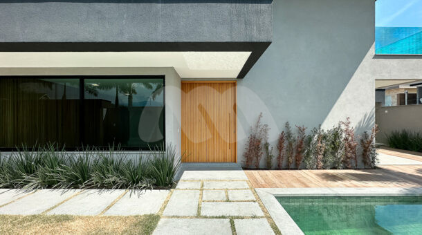 Imagem da área externa com a porta de madeira da sala da casa à venda em luxuoso condomínio.