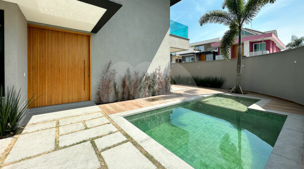 Imagem da área externa com a porta de madeira e piscina da sala da casa à venda em luxuoso condomínio.
