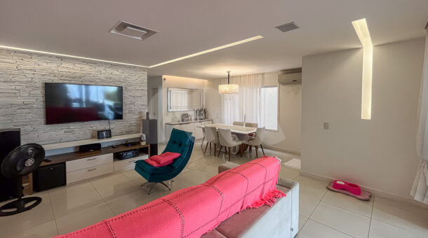 Imagem de sala ampla com iluminação planejada em led, sofa, tv e area de jantar em casa triplex a venda no rio de janeiro
