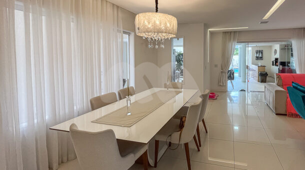 Imagem de sala de jantar com mesa de jantar branca, 6 cadeiras confortaveis, lustre e cortinas voeil lindas em casa a venda
